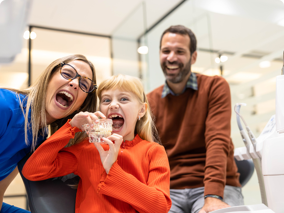 Child with dentist and parent, smiling together.