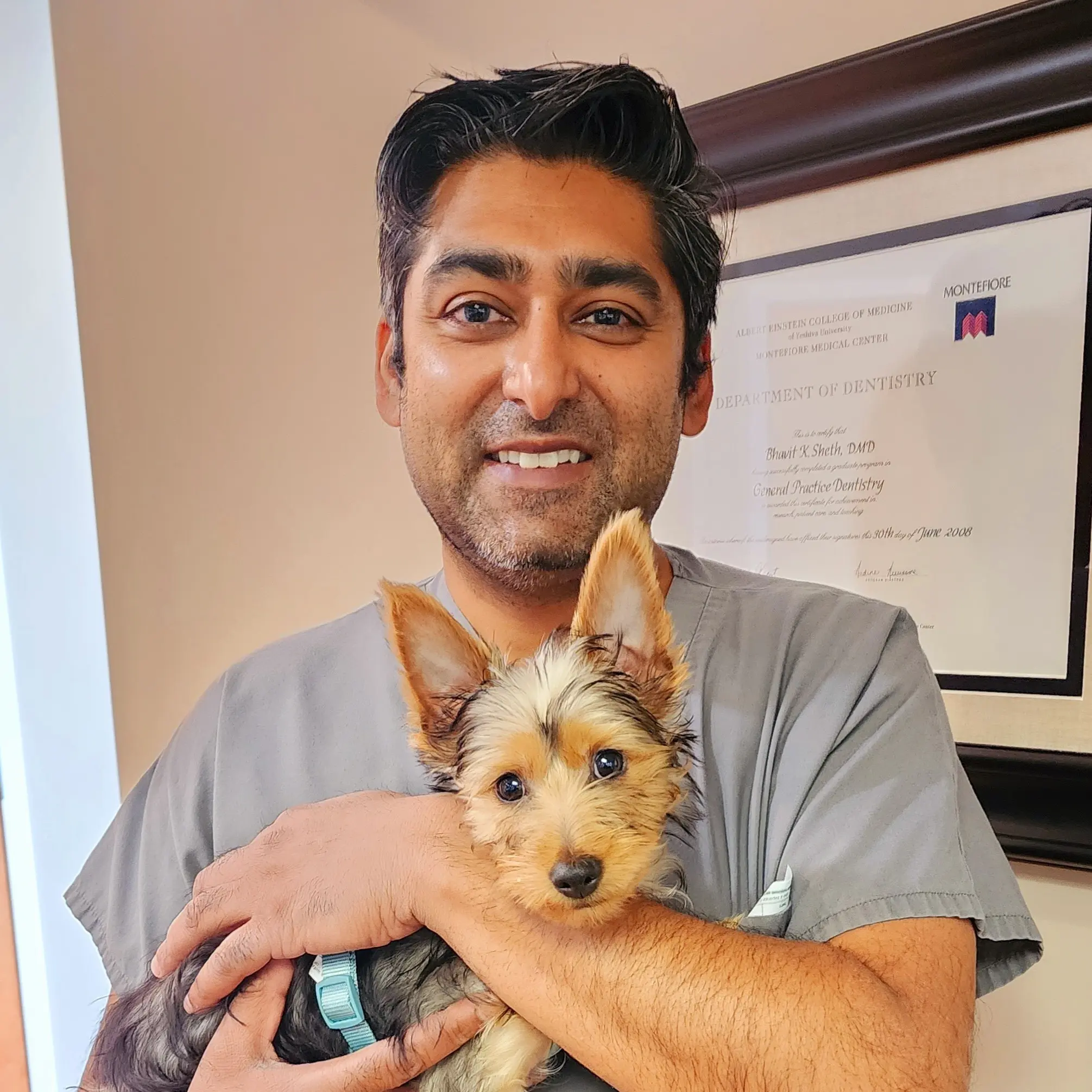 Smiling man holding a small dog indoors.